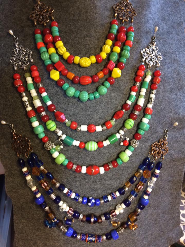 Flera vikingainspirerade pärlhalsband med glaspärlor i olika färger, upphängda på marknadsställ.