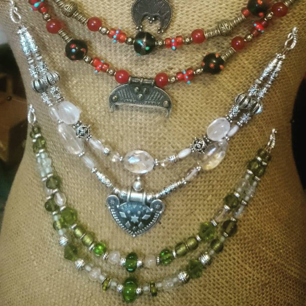 Flera vikingainspirerade pärlhalsband med glaspärlor och halsbandsbucklor i metall, upphängda på marknadsställ.