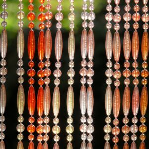 Närbild av hängande pärlsträngar i varma toner där upprepade mönster skapar symmetri med små variationer i färg och transparens